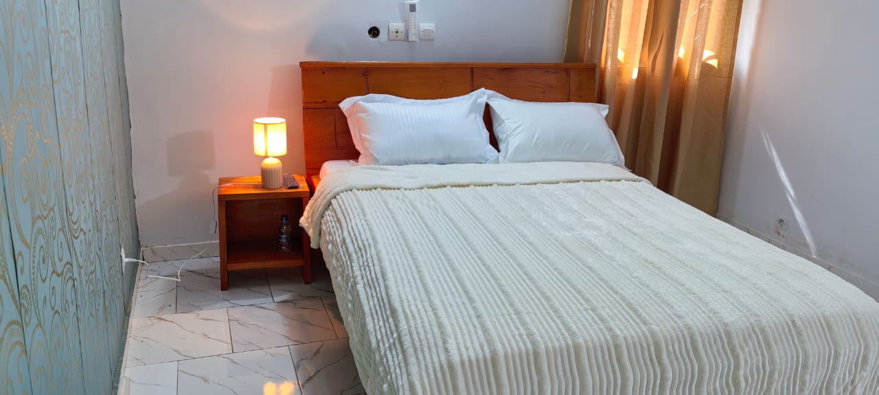 Chambre cosy crème avec lampe de chevet allumée et couette texturée