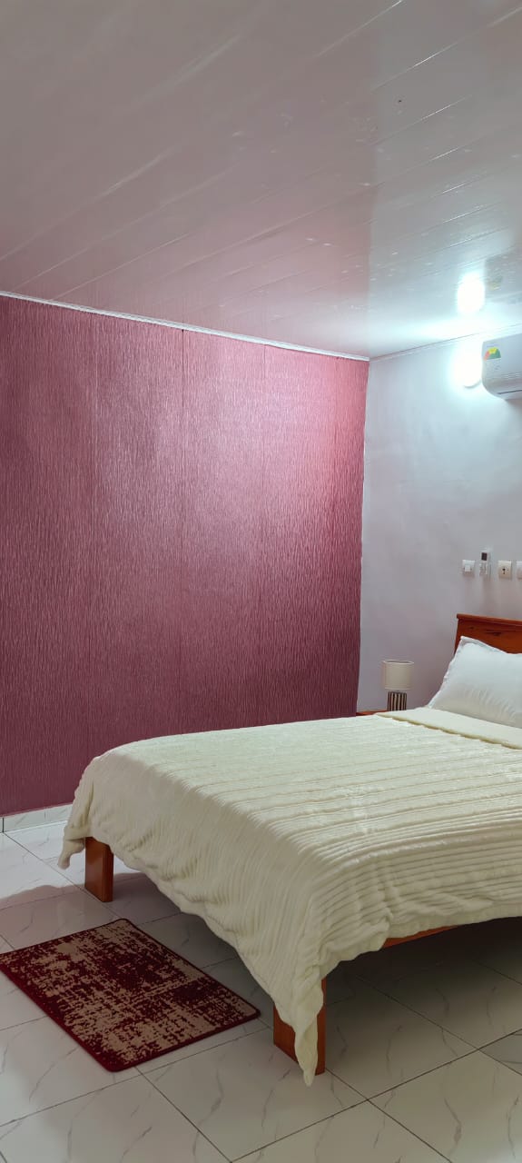Chambre avec mur rose, lit double et couette blanche